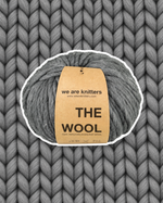 The Wool Spotted Dark Grey yarn ball on a matching knit swatch