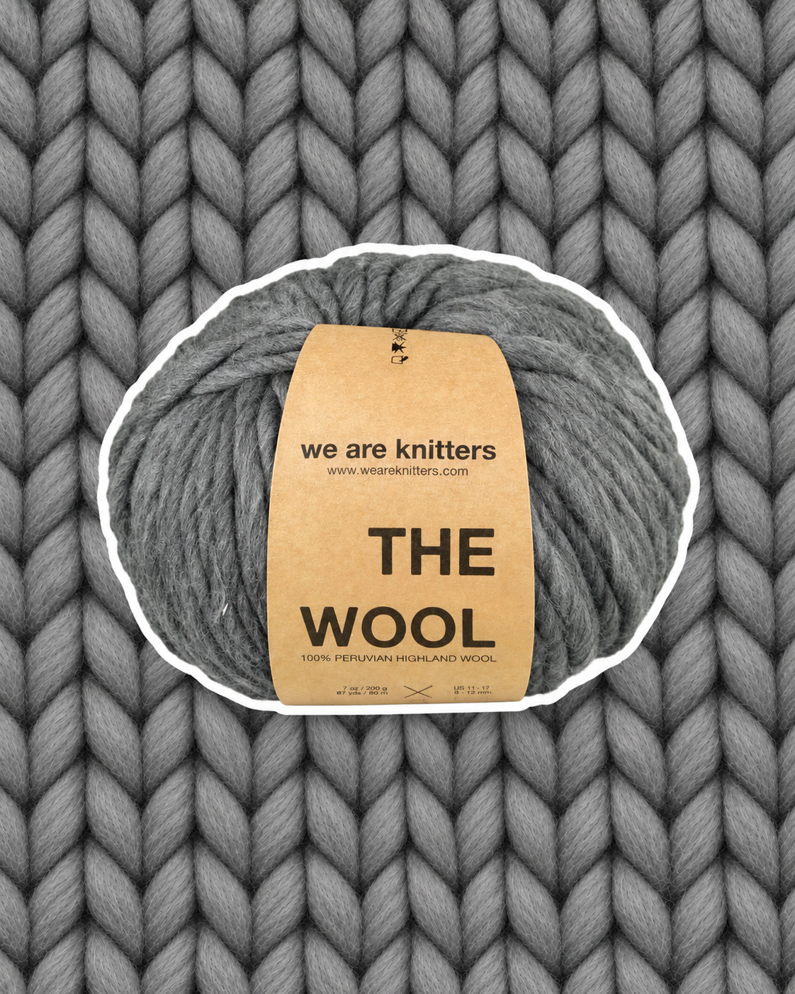 The Wool Spotted Dark Grey yarn ball on a matching knit swatch